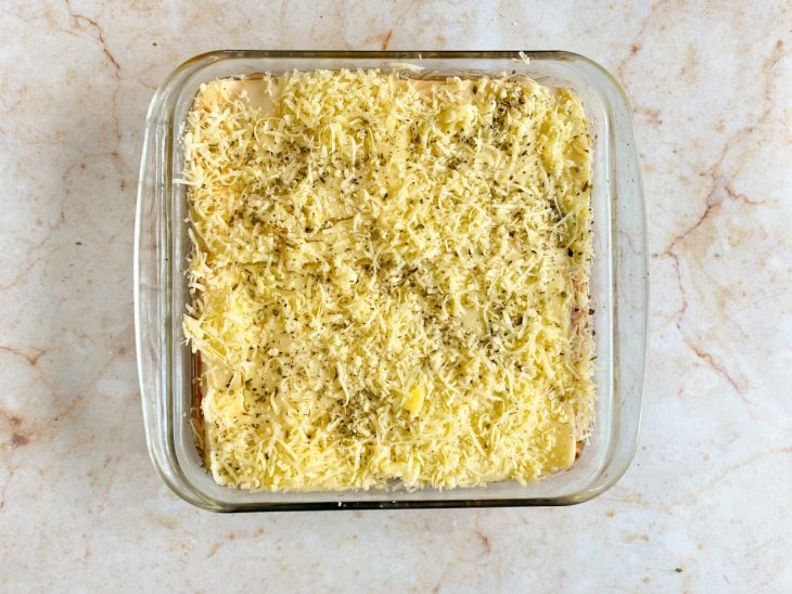 Lasanha finalizada com uma camada de parmesão e orégano.