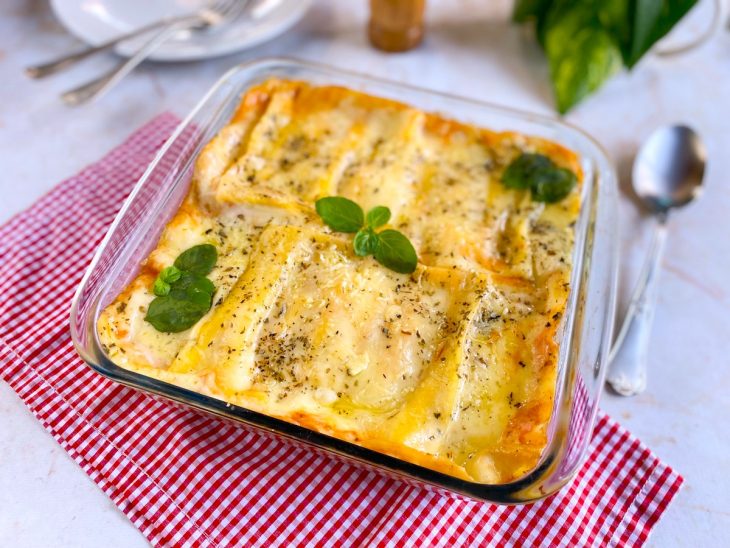 Lasanha rápida de presunto e queijo finalizada com folhas de manjericão e pronta para servir.