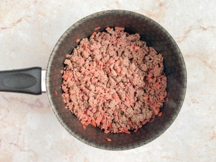 Panela com um fio de óleo, mortadela e carne moída.