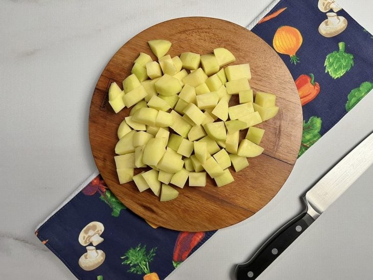 Tábua com batatas cortadas em cubos.