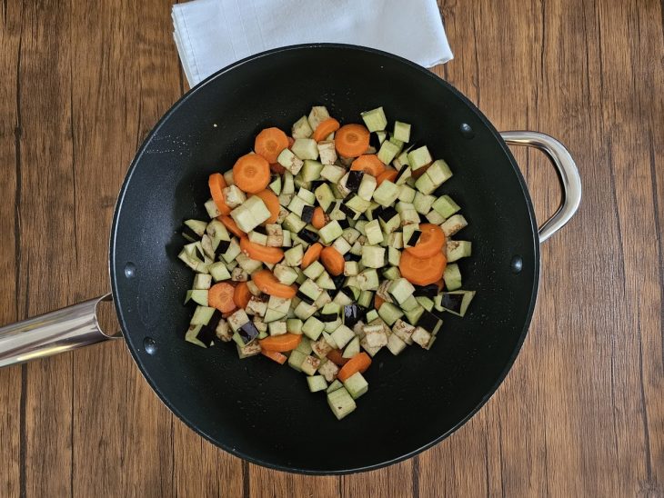 Uma frigideira com azeite, cenoura e berinjela.