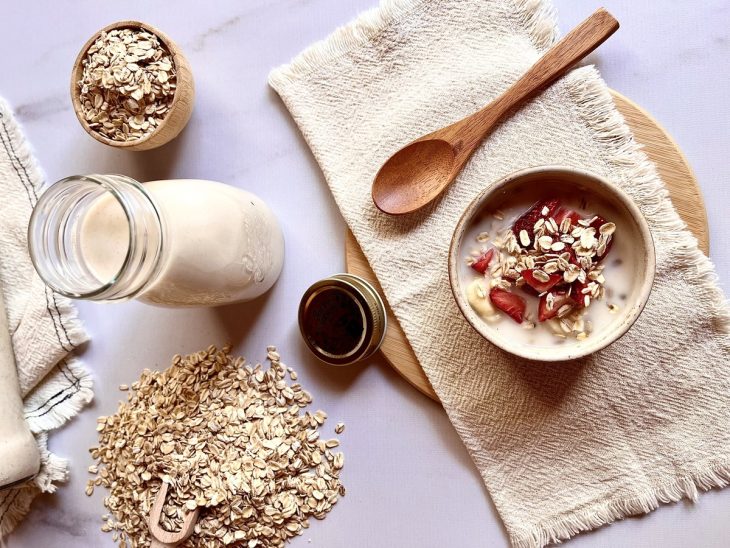 Garrafa de vidro com o leite de aveia e uma vasilha com leite de aveia frutas.