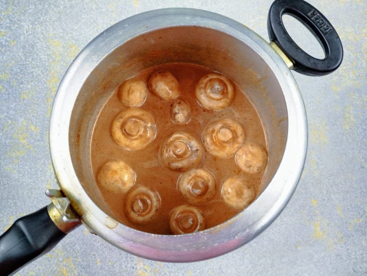 Uma panela de pressão com o molho e cogumelos.