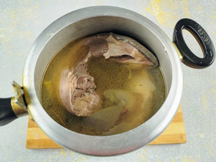 Uma panela de pressão com água e a carne cozida.