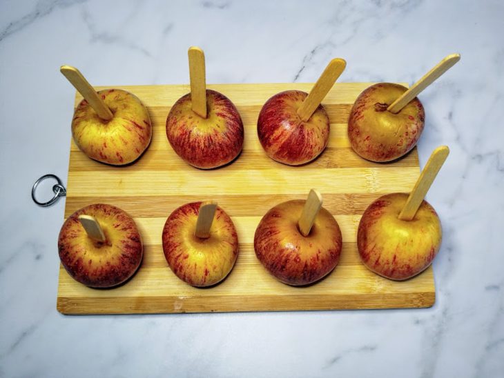 Uma tábua com maçãs fixadas em palitos.
