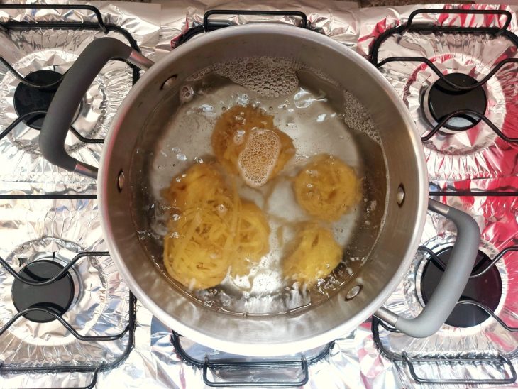 Uma panela contendo água fervente cozinhando o macarrão.