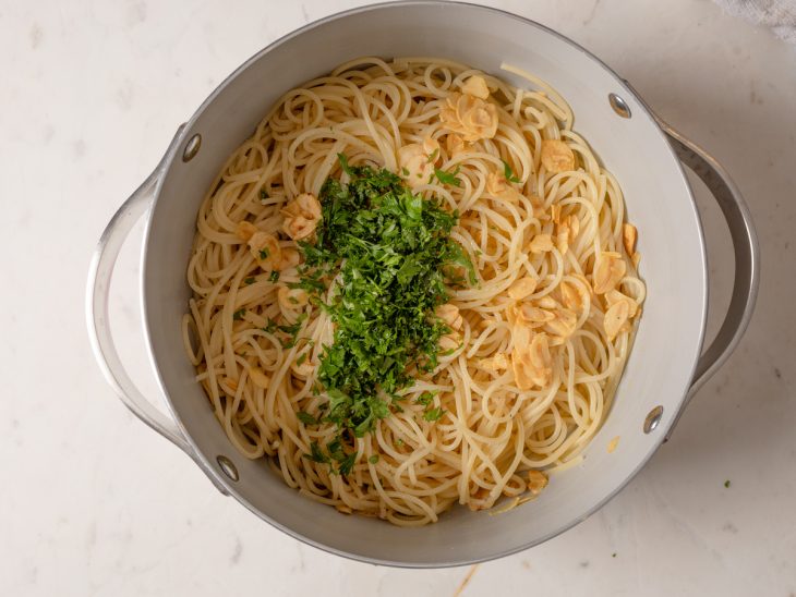 Salsinha picada adicionada ao macarrão na panela.