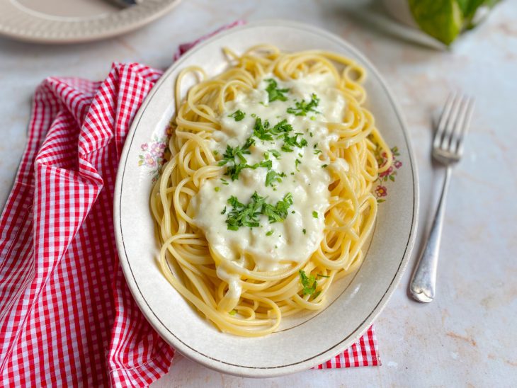 Macarrão ao molho branco sem creme de leite pronto para consumo e finalizado com cebolinha.