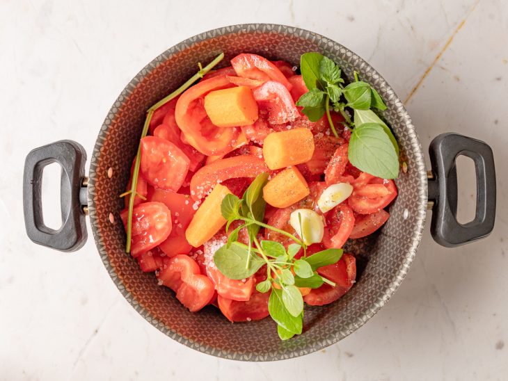 Alho, tomate, cenoura, manjericão, azeite e água em uma panela.