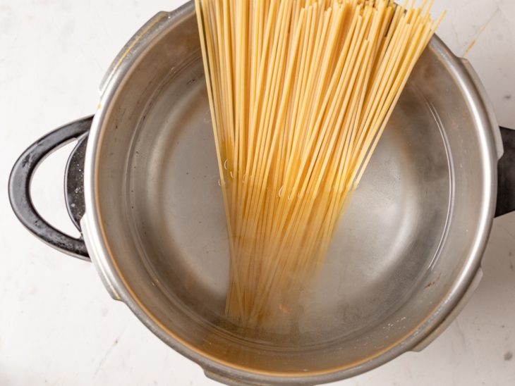 Macarrão cru em uma panela com água.