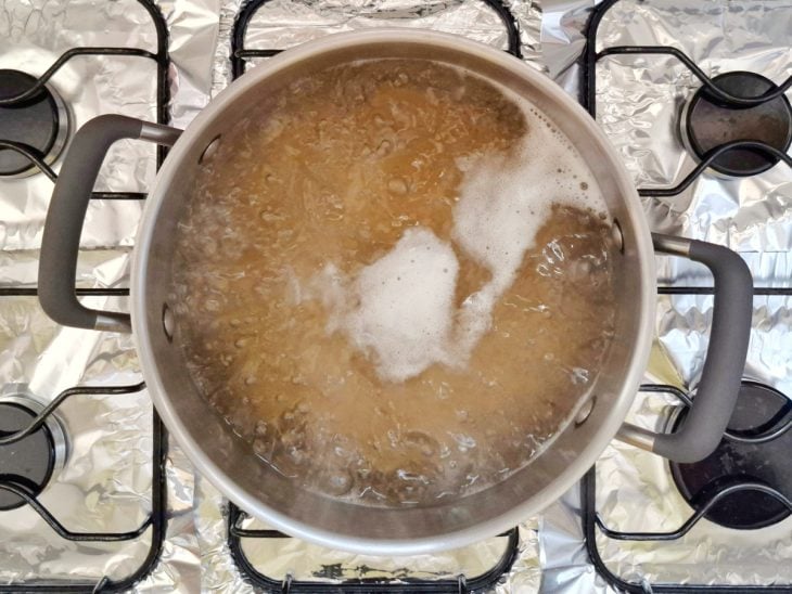 Macarrão cozinhando em água fervida no fogão.