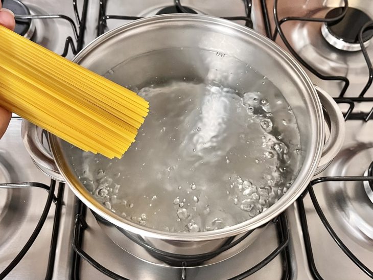 Uma panela ao fogo com água e macarrão.