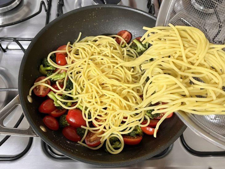 Uma panela com a mistura do macarrão e os vegetais.