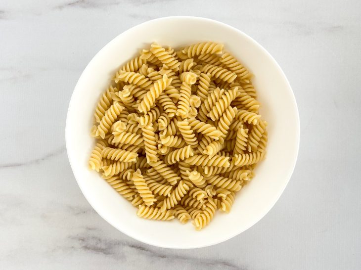 Macarrão em uma tigela com fio de azeite adicionado.