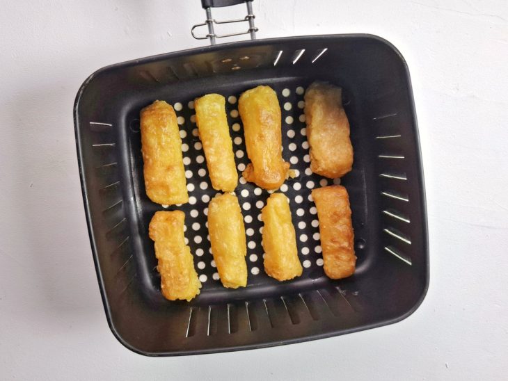 Uma cesta de air fryer com os pedaços de mandioca.