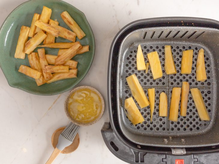 Um cesto de air fryer com pedaços de mandioca.