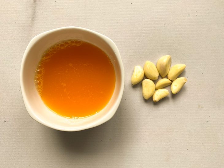 Alhos e um recipiente com suco de laranja.