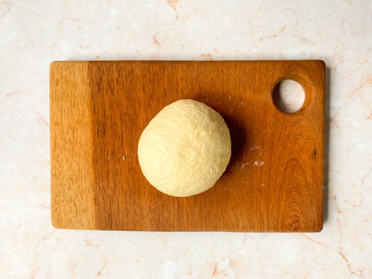 Massa de pizza profissional sovada sobre uma tábua com farinha salpicada.