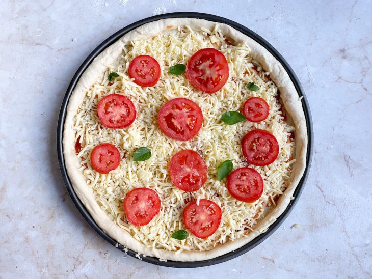 Recheio acomodado sobre a massa de pizza na forma.