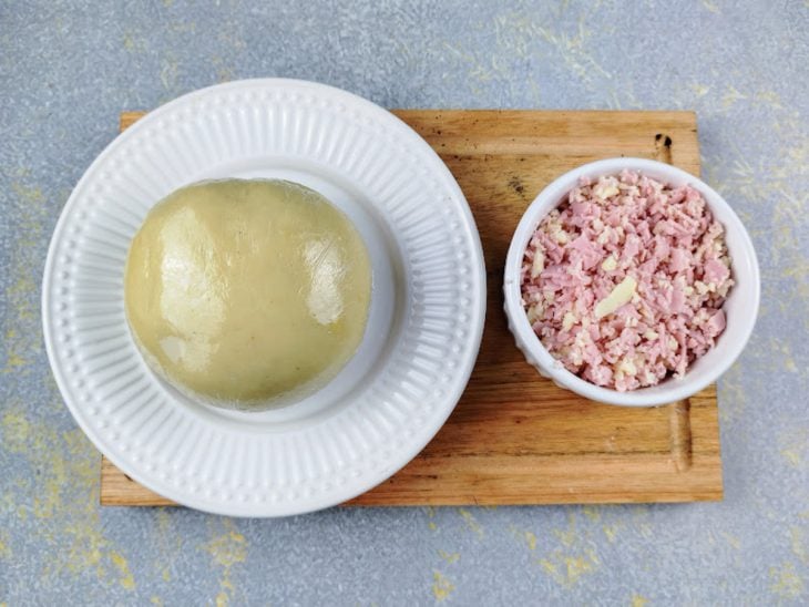 prato com massa de salgado frito. Recipiente com presunto e queijo ralados