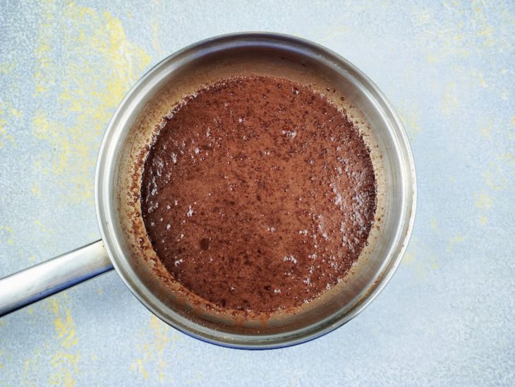 Uma panela com chocolate em pó, água e açúcar.