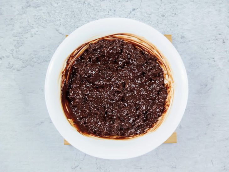 Uma tigela com chocolate derretido, creme de leite e flocos de Ovomaltine.