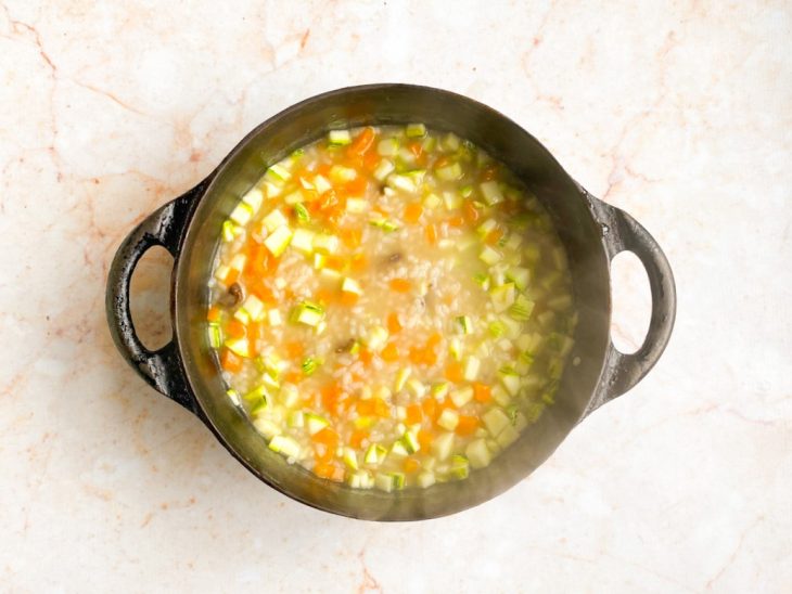 panela com água, arroz, cenoura e abobrinha