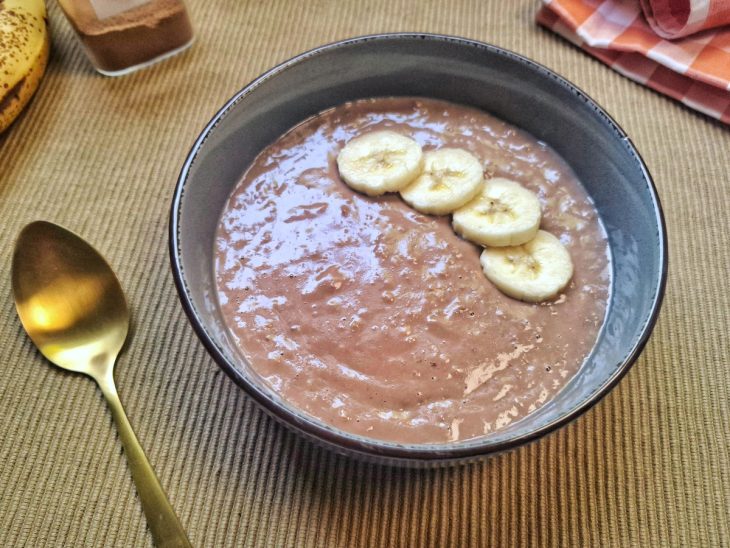 Mingau de aveia com YoPro em uma tigela com rodelas de bananas na superfície.