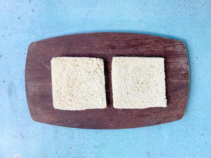 Uma tábua contendo duas fatias de pão de forma.