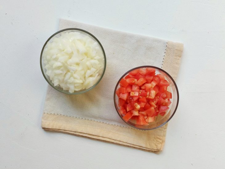 Dois recipientes com cebola e tomate picados.