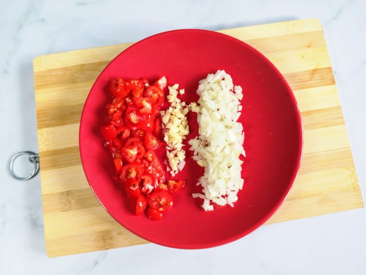 Um prato com tomate, cebola e alho picados.