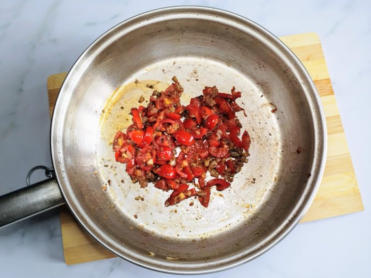 Uma frigideira com alho, cebola, pimenta-do-reino, orégano e tomates-cereja.