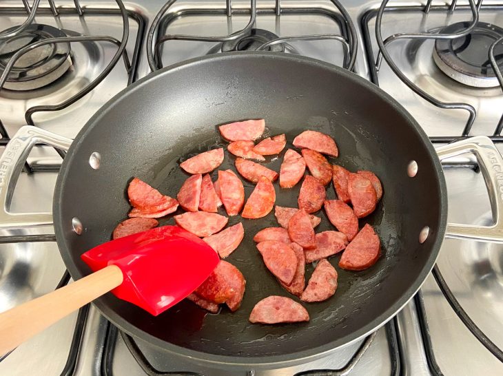 Uma frigideira com calabresa a dourar no óleo.