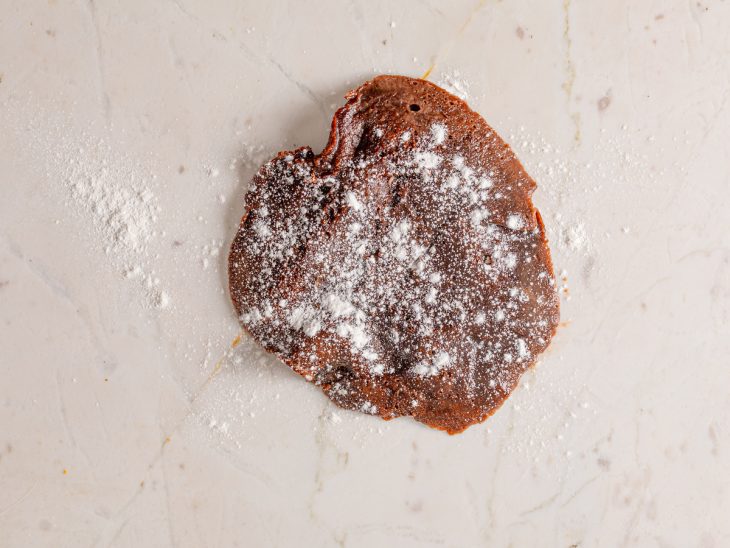 Massa do mochi colocada em uma bancada com farinha salpicada por cima.