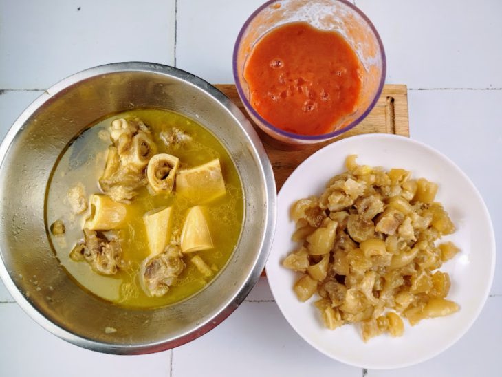 tigela com molho de tomate. Prato com mocotó picado. Tigela com caldo de mocotó