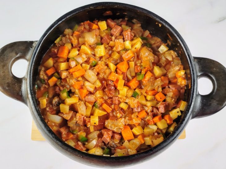 Mocotó, cenoura, batata, molho de tomate, colorau e pimenta-do-reino adicionados a panela.