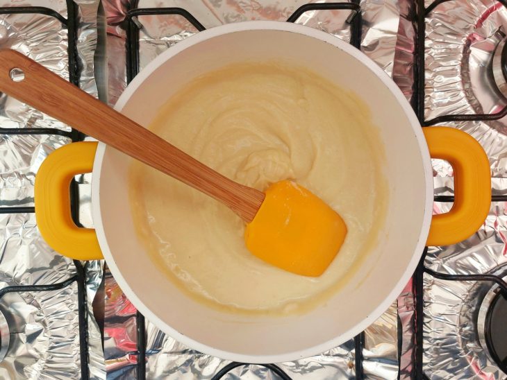Uma panela com margarina, farinha peneirada e leite.