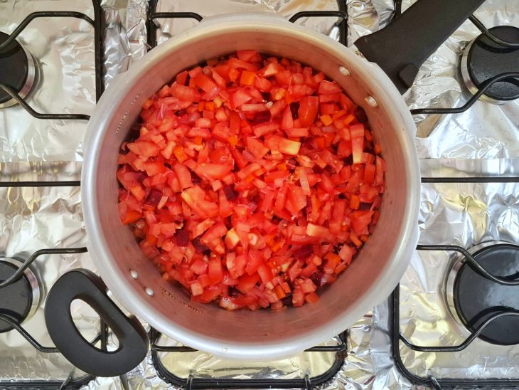 Azeite, cebola, alho, tomate, e cenoura em uma panela.