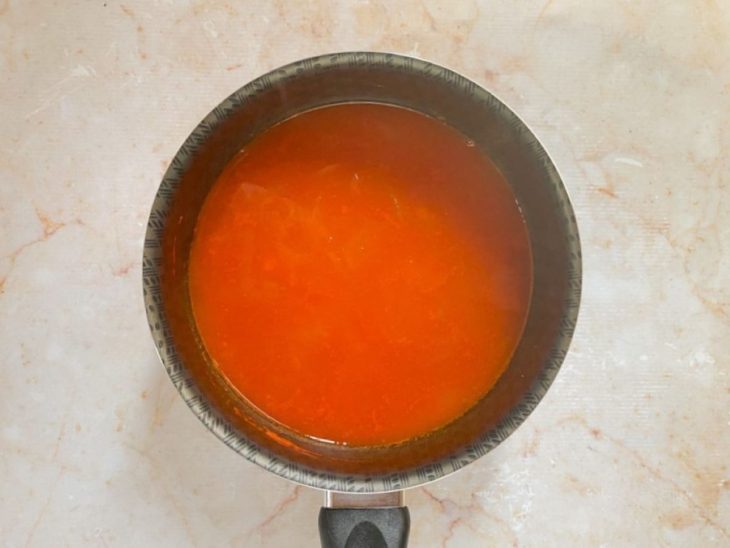 Suco de tomate coado e temperado com sal em uma panela.