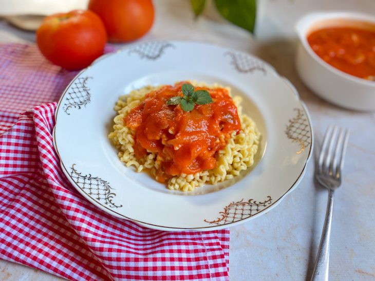 Porção de molho sugo despejada sobre a massa em um prato.