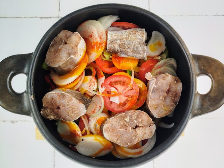 panela com rodelas de pimentão, cebola e tomate, além de filés de piramutuba