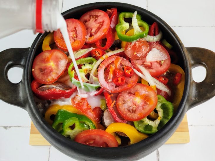 panela com rodelas de pimentão, cebola e tomate, além de filés de piramutuba e leite de coco