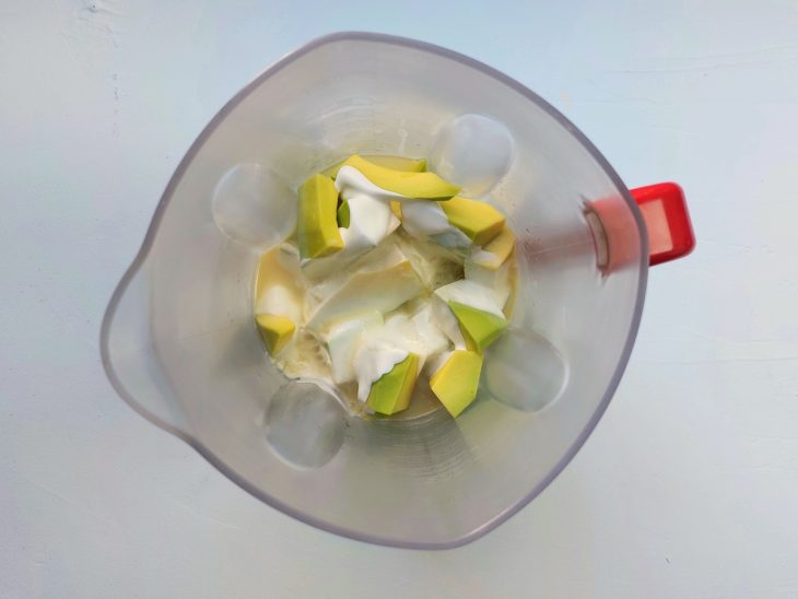Um liquidificador com abacate picado, leite condensado, creme de leite e suco de limão.