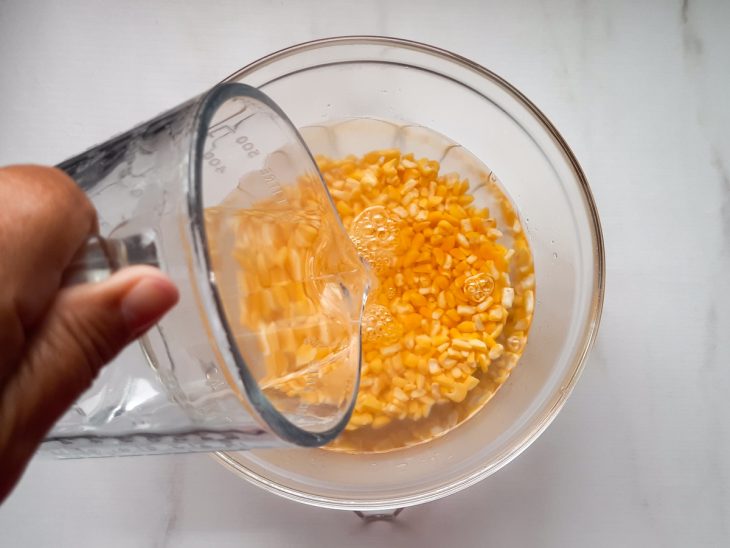 Um recipiente contendo milho amarelo de molho na água quente.