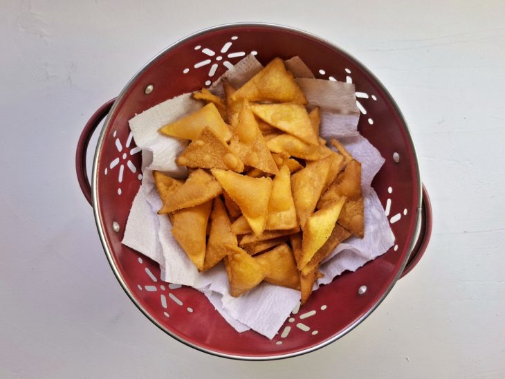 Tortilhas de milho fritas e escorrendo em uma tigela com papel-toalha.