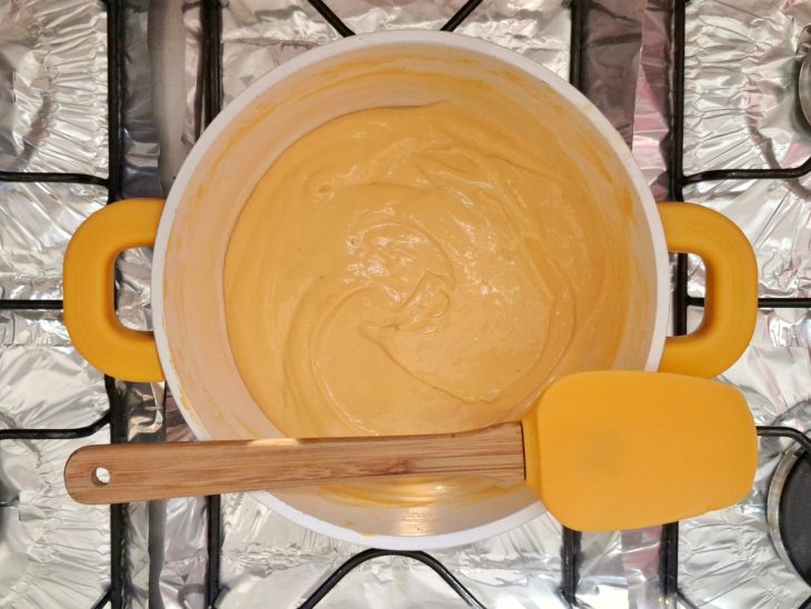 Panela com molho de queijo com coloração mais amarelada.