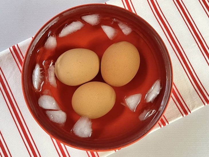 Um recipiente contendo água gelada com ovos cozidos.