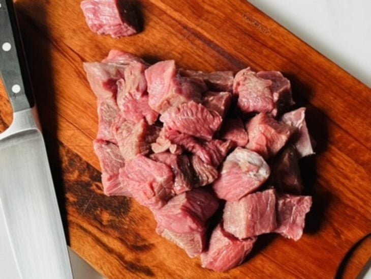 Carne cortada em cubos sobre uma tábua.