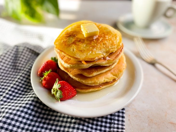 Panquecas americanas fáceis finalizadas com mel, manteiga e morangos.