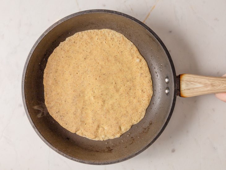 Massa de panqueca com farinha de banana-verde em uma frigideira.